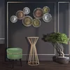 A stylish interior scene featuring a decorative wall art, a green stool, a gold plant stand, and a bonsai tree. Produktbild-Vorschau