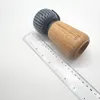 A salt or pepper mill with a wooden base and a ribbed gray top sits next to a clear ruler on a white background. Podgląd zdjęcia produktu