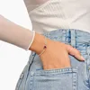 A woman's hand with a bracelet is placed in the pocket of her jeans. Podgląd zdjęcia produktu