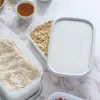 A close-up overhead shot of Tupperware storage containers filled with dry goods like oats and flour, with a small bowl of honey nearby. Produktbild-Vorschau