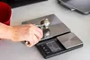 A person's hand is holding an ice cream scoop over a digital kitchen scale. Voir les images du produit