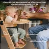 A baby is being fed in a high chair at a table with other people in the background. Voir les images du produit