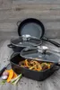 A collection of cookware, including a frying pan and two lidded pots, arranged on a wooden surface. Some ingredients like garlic, onion, and pumpkin are placed in the foreground. Podgląd zdjęcia produktu