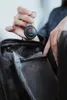A person is holding a black key finder over an open black bag. Podgląd zdjęcia produktu