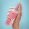 A hand holding a pink spray bottle with water droplets on it, against a blue background. Náhľad obrázku produktu