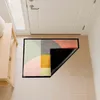 A doormat with a geometric pattern is placed on a tiled floor in front of a white door. Part of the doormat is lifted to show its black backing. Produktbild-Vorschau
