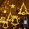 Christmas lights in the shape of stars, trees, bells, and a reindeer, hanging against a dark, blurred background, with a power adapter visible on the right. Náhled obrázku produktu
