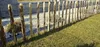 A rustic wooden fence bordering a garden with grass and gravel. Produktbild-Vorschau
