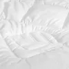A close-up view of a white quilted blanket or duvet. Produktbild-Vorschau