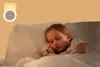 A young girl sleeping in bed with a teddy bear, illuminated by a night light. Podgląd zdjęcia produktu