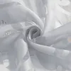 A close-up view of a white sheer fabric with a subtle pattern and text printed on it, swirled into a spiral. Produktbild-Vorschau