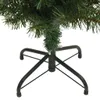 A close-up view of the base and lower branches of an artificial Christmas tree, showing its green needles and black metal stand. Podgląd zdjęcia produktu