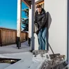 A man is shoveling snow from a wooden deck on a sunny day. Produktbild-Vorschau