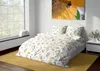 A bedroom scene with a bed made with floral patterned bedding, a large window, and a painting of a sunflower with a bee. Náhled obrázku produktu