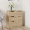 A wooden sideboard with six drawers, a vase of white flowers on top, and a gray chair to the side, set against a white wall. Náhled obrázku produktu
