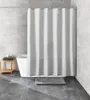A modern bathroom with a white bathtub, a gray shower curtain, and a wooden stool with towels. Produktbild-Vorschau
