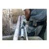 A construction worker is using a reciprocating saw to cut a pipe in a trench. Náhľad obrázku produktu