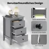 A grey nightstand with three drawers is shown, along with close-up images highlighting its features like metal drawer slides, round knobs, and an anti-tip kit. A lamp, books, and an alarm clock are on top of the nightstand. Podgląd zdjęcia produktu