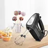 A black Bosch hand mixer is displayed on a wooden surface next to cupcakes and cake pops. Produktbild-Vorschau