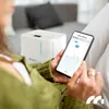 A person is holding a smartphone displaying a graph, next to a white dehumidifier. Voir les images du produit