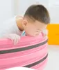 A young boy is leaning over a pink and black striped object, possibly a balance board or a play item. Podgląd zdjęcia produktu