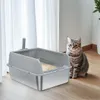 A cat sits next to an open litter box in a room with white curtains. Produktbild-Vorschau