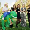 A group of people posing outdoors with one person riding an inflatable dinosaur costume. Náhled obrázku produktu