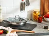A kitchen counter with a frying pan, vegetables, and jars of food. Podgląd zdjęcia produktu