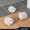 Three toilet brush heads are placed on a wooden slatted mat on a tiled floor next to a bath mat. Produktbild-Vorschau