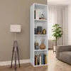 A tall, narrow white bookshelf filled with decorative items and books, placed in a living room setting next to a floor lamp and a sofa. Náhled obrázku produktu