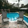 Two chairs are placed on a stone patio next to a swimming pool, surrounded by lush greenery and palm trees. Podgląd zdjęcia produktu