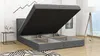 A boxspring bed with its storage compartment open, in a room with a side table and a floor lamp. Produktbild-Vorschau