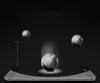 Several metallic spheres are shown in motion, with one sphere resting on a smartphone screen, suggesting impact resistance. Náhled obrázku produktu