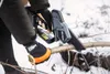 A person wearing gloves is using a mini chainsaw to cut a branch in a snowy environment. Podgląd zdjęcia produktu