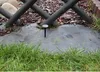 Ground cover fabric with stakes in a garden setting, next to grass and a wooden fence. Náhľad obrázku produktu