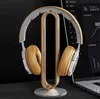 A pair of headphones rests on a wooden stand, with a laptop screen visible in the background. Produktbild-Vorschau