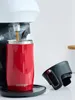 A red Contigo travel mug is being filled with coffee from a coffee machine. A black lid is placed next to the mug. Náhľad obrázku produktu