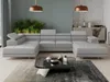 A modern living room with a large sectional sofa, coffee table, and plants.