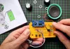 Hands assembling an electronic kit on a grid mat. Podgląd zdjęcia produktu