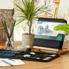 A drawing set is open on a wooden table, with art supplies and a plant in the background. Podgląd zdjęcia produktu