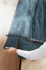 A person is using a steam cleaner to remove wrinkles from a teal jacket. Produktbild-Vorschau