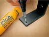 A hand is using a marker to mark a hole in a metal bracket. A yellow marker tube is next to the bracket. Produktbild-Vorschau