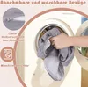 A hand is putting a gray fabric into a washing machine. The image also contains text and icons related to product features. Voir les images du produit