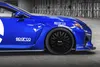 A close-up of a blue car with Sparco logos on the side and fender, parked indoors. Produktbild-Vorschau