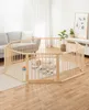 A baby is playing inside a wooden playpen in a living room. Voir les images du produit