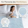 A woman sleeping peacefully in a bed, covered by a light blue blanket. Produktbild-Vorschau