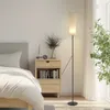 A bedroom scene with a bed, nightstand, and a floor lamp. Anteprima dell’immagine prodotto