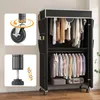A portable wardrobe filled with clothes, shown with close-ups of its wheels and adjustable feet. Produktbild-Vorschau