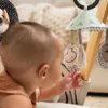 A baby reaching for a toy on a play gym. Produktbild-Vorschau