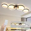 A hand holding a remote control is shown in the foreground, with a modern ceiling lamp with multiple rings illuminated in the background. Several inset images show the lamp with different lighting effects and color temperatures. Voir les images du produit